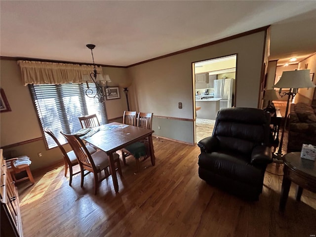 dining space with a chandelier, crown molding, wood finished floors, and baseboards