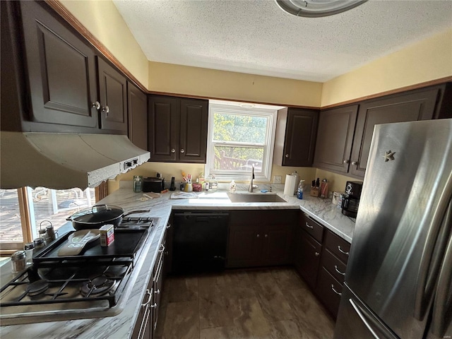 kitchen with appliances with stainless steel finishes, a sink, a textured ceiling, dark brown cabinetry, and range hood