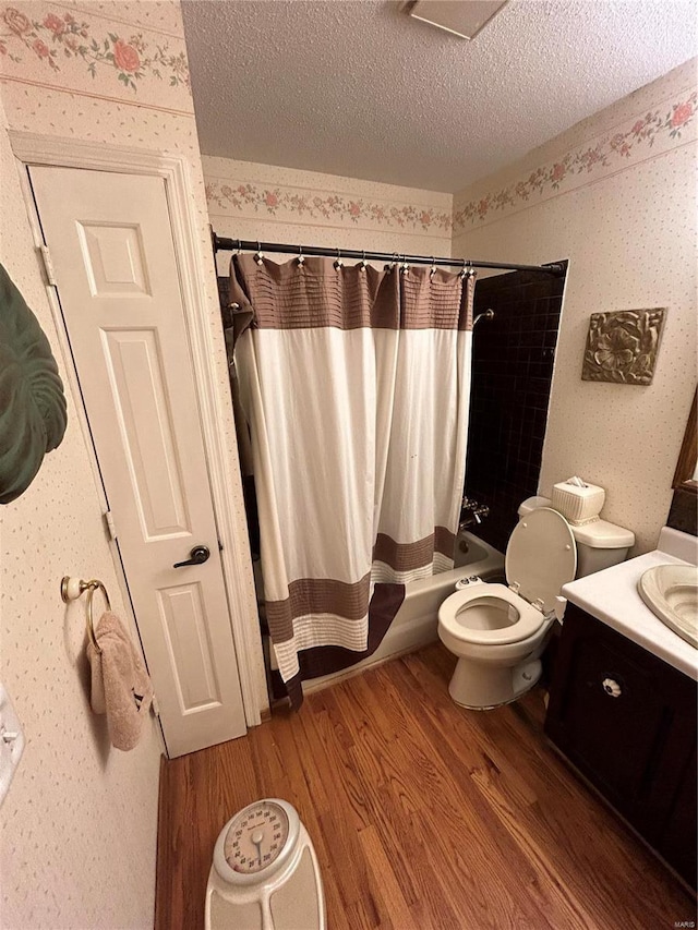 full bathroom with wood finished floors, a textured ceiling, shower / tub combo with curtain, toilet, and vanity