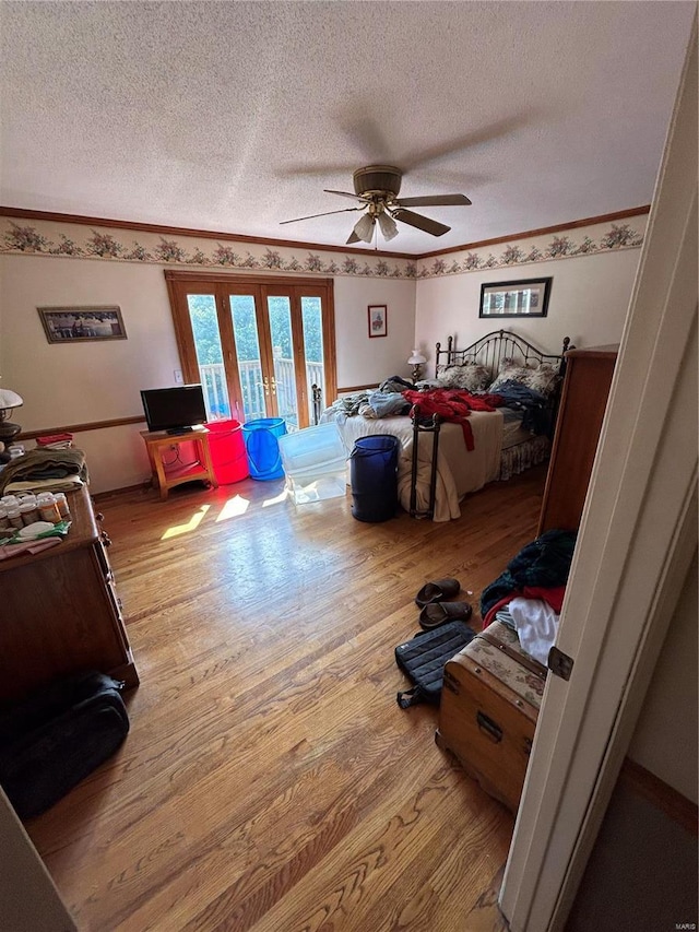 bedroom with a textured ceiling, wood finished floors, french doors, a ceiling fan, and crown molding