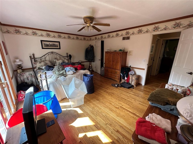 bedroom with wood finished floors, ornamental molding, and ceiling fan