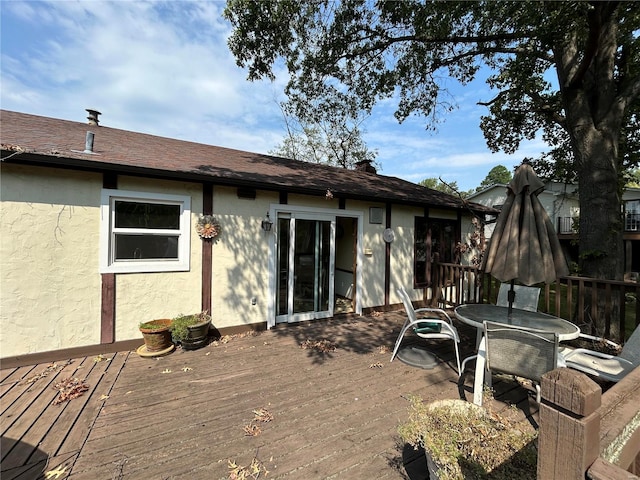 rear view of property featuring stucco siding and a deck