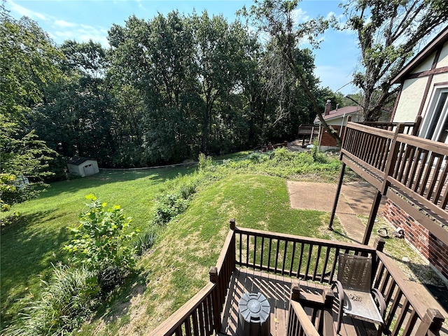 view of green lawn featuring a wooden deck, an outdoor structure, and a storage unit
