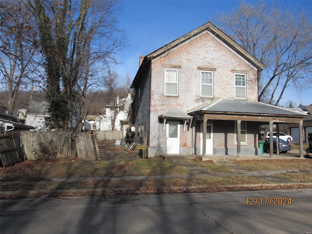 1101 S Carolina St, Louisiana, MO 63353 - view of front of home with fence, brick siding, a chimney, and covered porch