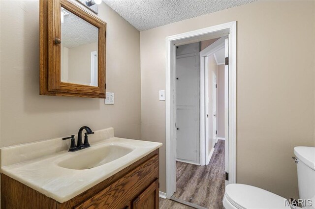 32 Summit St, Bonne Terre, MO 63628 - half bath featuring toilet, vanity, a textured ceiling, and wood finished floors