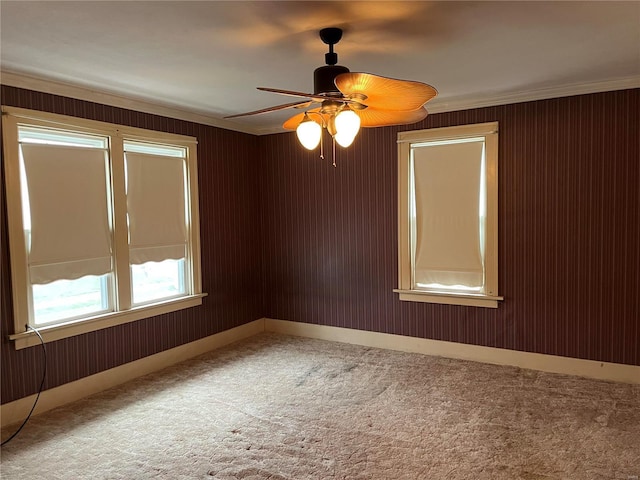 spare room featuring carpet flooring, crown molding, a ceiling fan, and baseboards