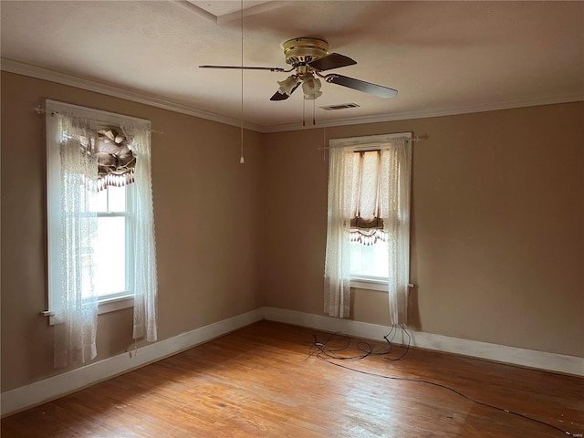 spare room featuring healthy amount of natural light, light wood-type flooring, a ceiling fan, baseboards, and crown molding