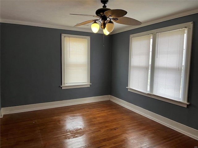 spare room with ornamental molding, wood finished floors, a ceiling fan, and baseboards