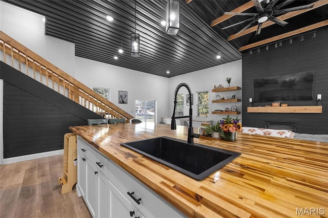 10410 Business 21, Hillsboro, MO 63050 - kitchen featuring butcher block counters, a sink, white cabinets, light wood-style floors, and decorative light fixtures