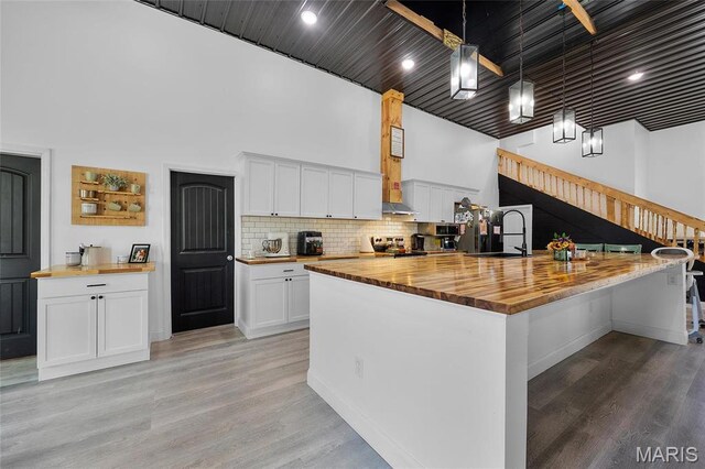 10410 Business 21, Hillsboro, MO 63050 - kitchen with wood counters, a sink, white cabinetry, light wood-style flooring, and a towering ceiling