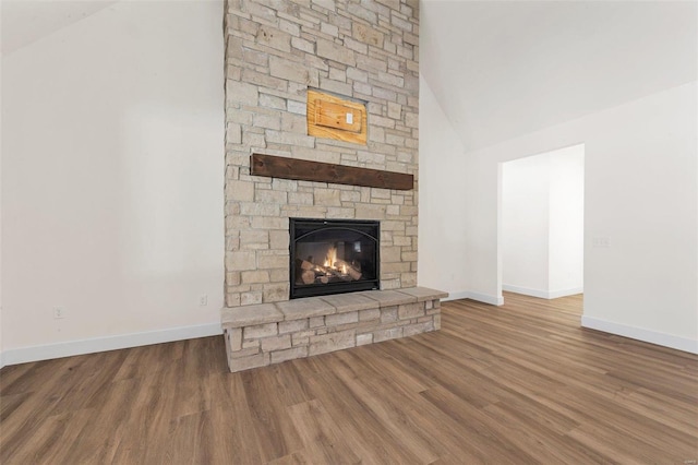 121 Spoonbill Ln, Foristell, MO 63348 - unfurnished living room with a stone fireplace, wood finished floors, baseboards, and high vaulted ceiling
