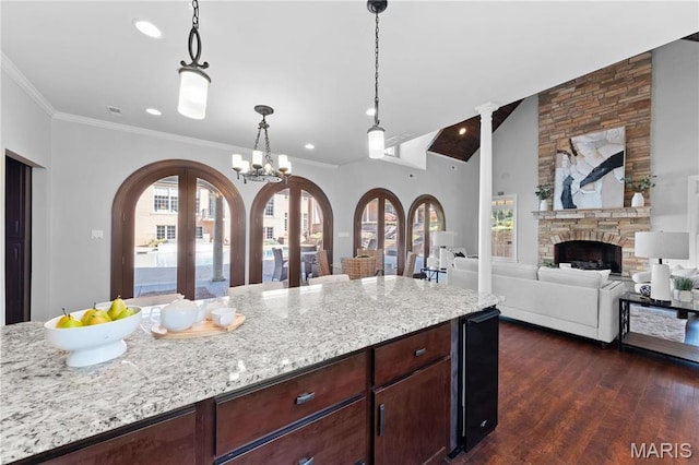 1 Claychester Dr, Saint Louis, MO 63131 - kitchen with arched walkways, dark wood-style flooring, a stone fireplace, light stone countertops, and decorative light fixtures