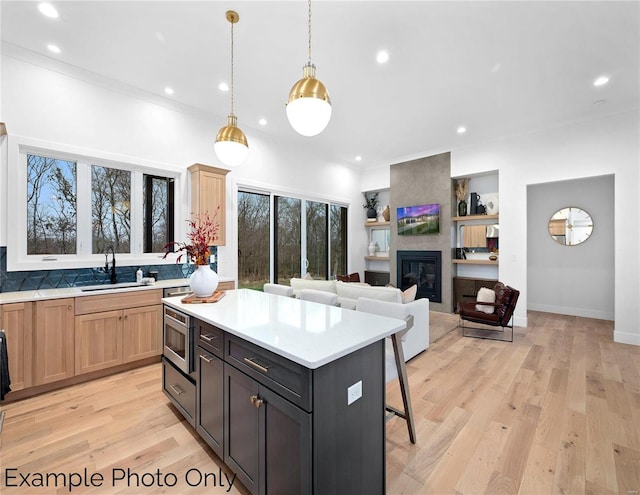 kitchen featuring a sink, light countertops, a kitchen bar, a kitchen island, and light wood-style flooring