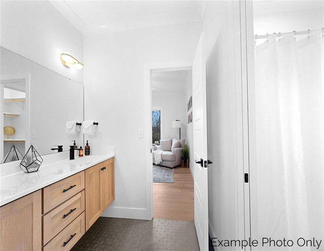 ensuite bathroom featuring vanity, baseboards, crown molding, and tile patterned floors