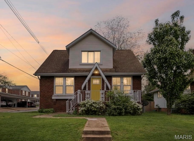 view of front of house featuring brick siding and a yard