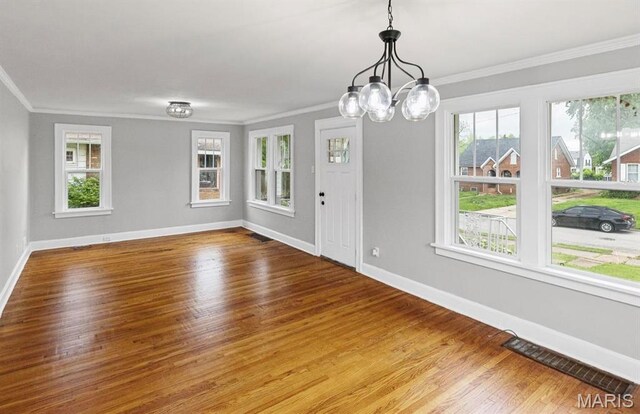 unfurnished dining area with ornamental molding, baseboards, wood finished floors, and a chandelier