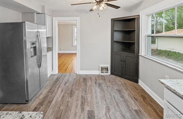 unfurnished dining area with wood finished floors, ceiling fan, and baseboards