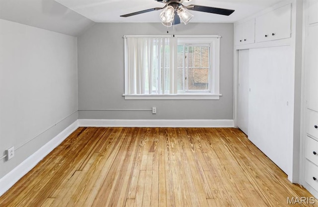 unfurnished bedroom featuring vaulted ceiling, light wood finished floors, baseboards, a closet, and ceiling fan
