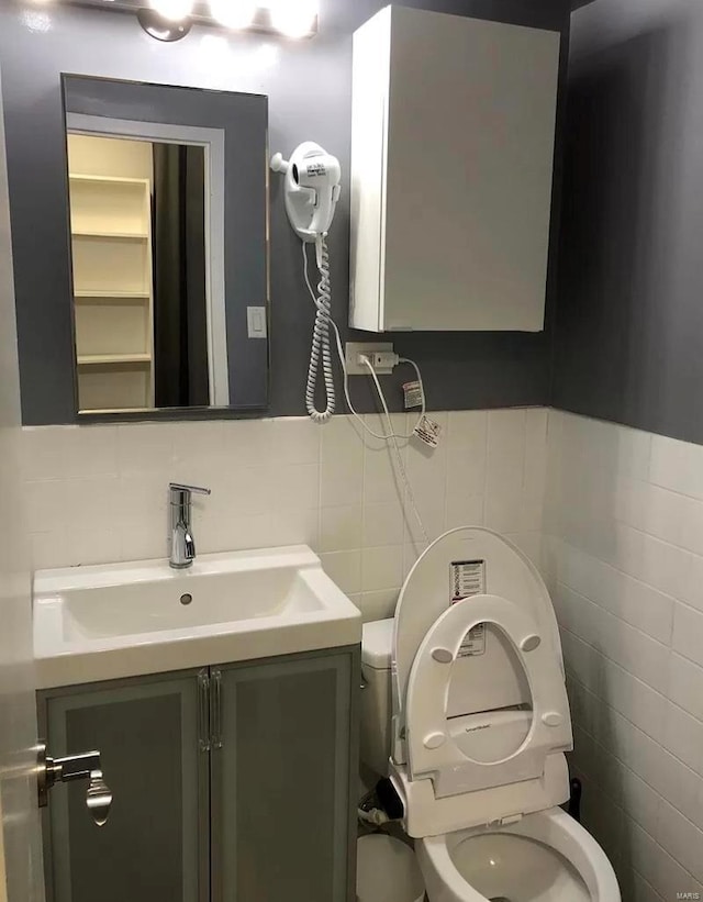 bathroom featuring tile walls, toilet, and vanity