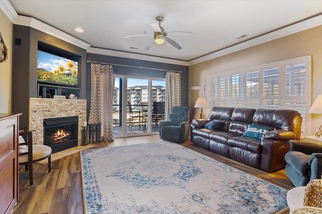 living room with ceiling fan, crown molding, wood finished floors, a stone fireplace, and recessed lighting