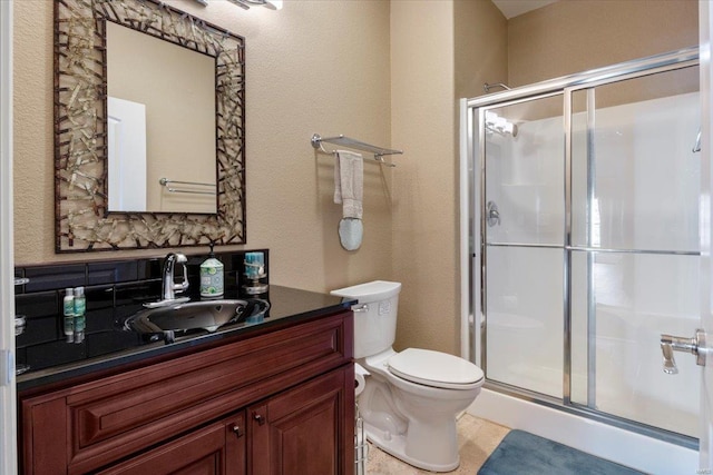 bathroom featuring a shower stall, vanity, toilet, and a textured wall