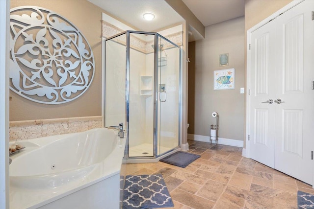 bathroom with a stall shower, a jetted tub, and stone tile flooring