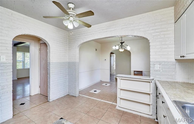509 Royal Ave, Ferguson, MO 63135 - kitchen featuring tile countertops, white cabinets, light tile patterned flooring, arched walkways, and a textured ceiling