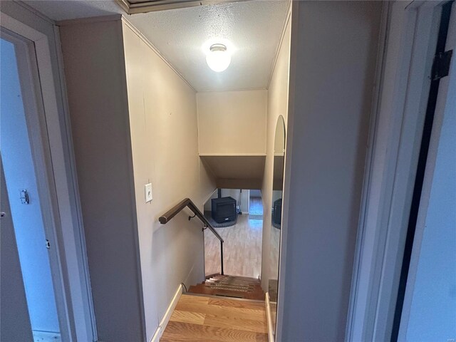 stairs with wood finished floors and a textured ceiling