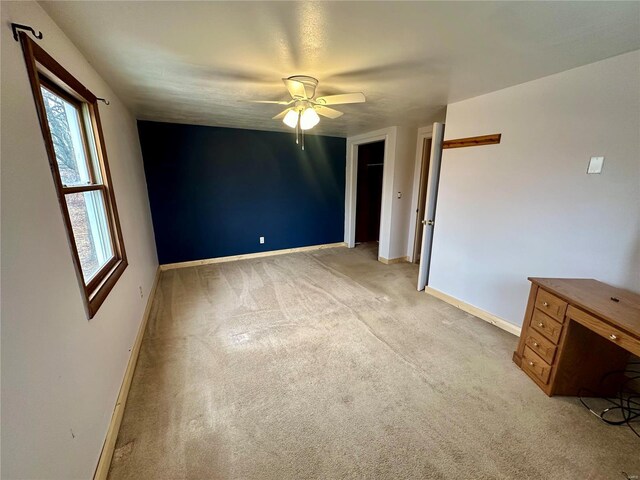 unfurnished bedroom with baseboards, light colored carpet, and a ceiling fan