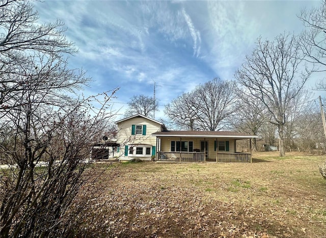 back of house with covered porch and a yard