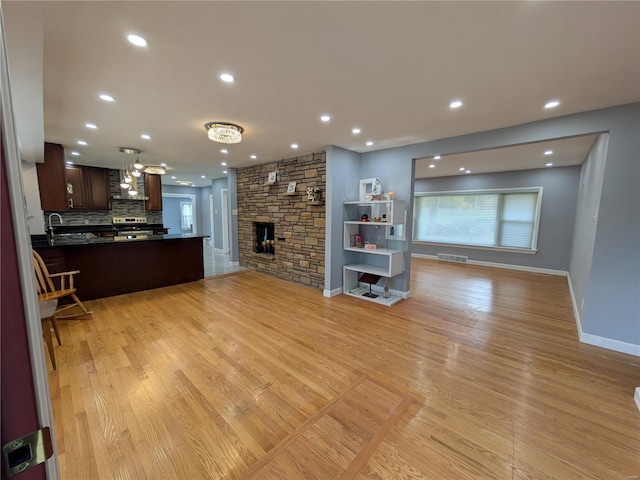 7 Carole Ln, Frontenac, MO 63131 - unfurnished living room with light wood-type flooring, a stone fireplace, recessed lighting, and baseboards
