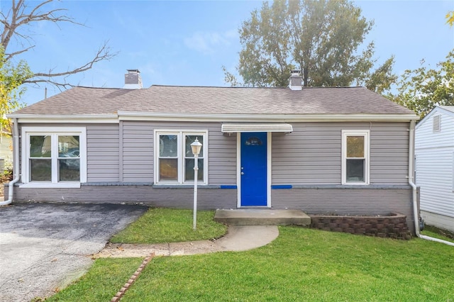 9608 Flora Ave, Saint Louis, MO 63114 - view of front of house with a chimney, a front lawn, brick siding, and a shingled roof