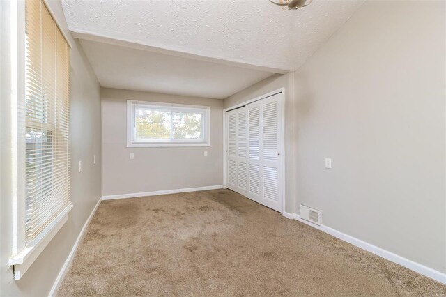 9608 Flora Ave, Saint Louis, MO 63114 - unfurnished bedroom featuring carpet flooring, a closet, a textured ceiling, and baseboards