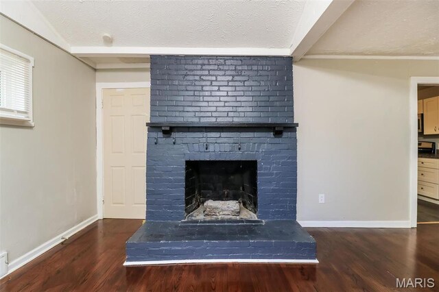 9608 Flora Ave, Saint Louis, MO 63114 - detailed view of a textured ceiling, wood finished floors, baseboards, and a brick fireplace