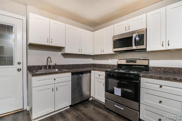 9608 Flora Ave, Saint Louis, MO 63114 - kitchen with stainless steel appliances, a sink, dark wood finished floors, and dark countertops