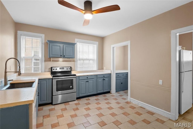 5099 Waterman Blvd, Saint Louis, MO 63108 - kitchen featuring stainless steel electric range oven, a sink, freestanding refrigerator, a ceiling fan, and light countertops