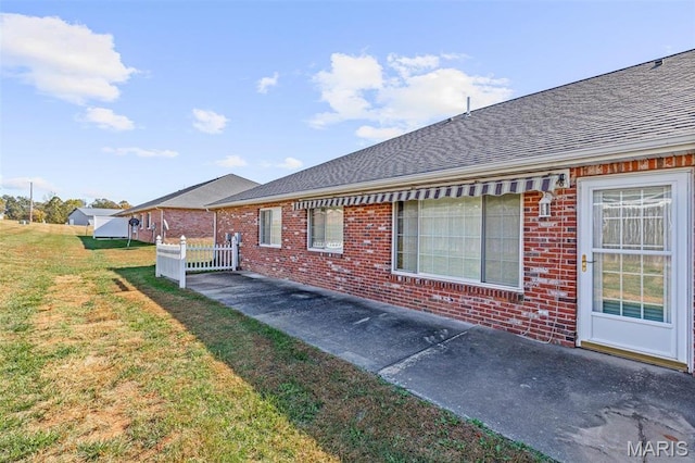 119 Ohio Ct, Farmington, MO 63640 - view of side of home with brick siding, roof with shingles, a lawn, and a patio