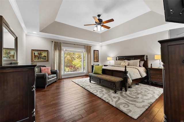 bedroom featuring a raised ceiling, dark wood-type flooring, crown molding, and ceiling fan