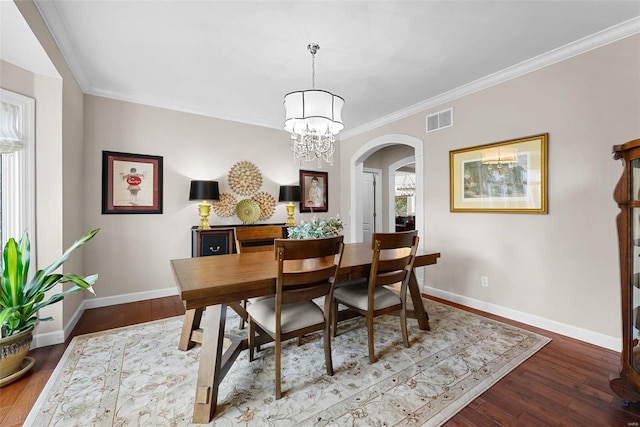 dining area with arched walkways, baseboards, hardwood / wood-style floors, a chandelier, and ornamental molding