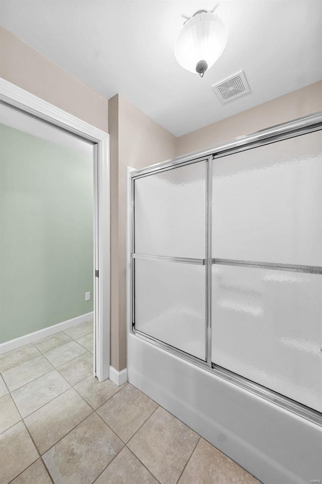 full bathroom featuring tile patterned flooring, bath / shower combo with glass door, and baseboards