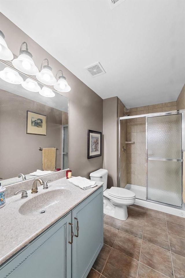 bathroom featuring toilet, a shower stall, vanity, and tile patterned flooring