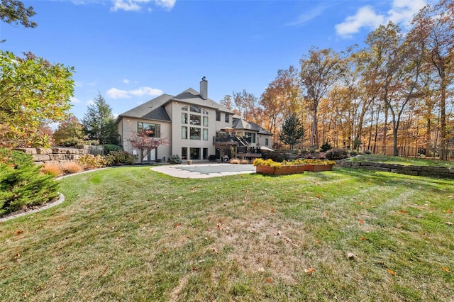 rear view of house featuring a patio area, a chimney, a lawn, and a wooden deck