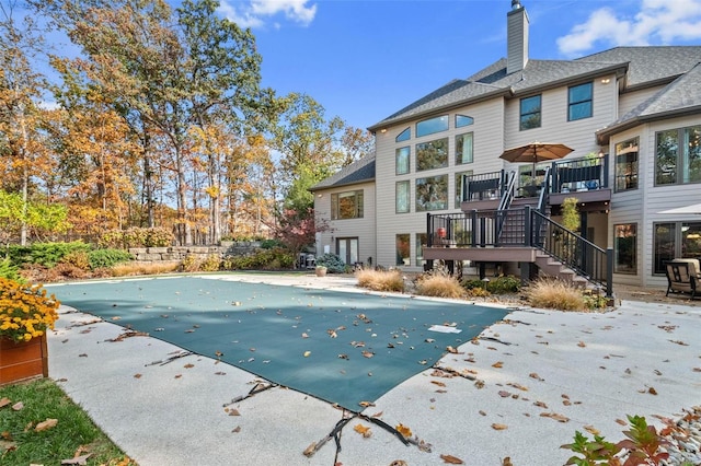 view of swimming pool with a patio area, a wooden deck, stairway, and a covered pool