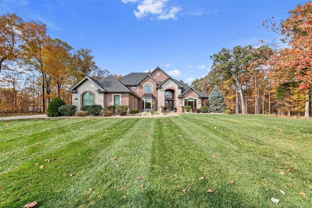 french provincial home featuring brick siding and a front lawn