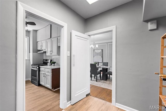 625 S Skinker Blvd Unit 202, Saint Louis, MO 63105 - kitchen with gas range, under cabinet range hood, light wood-style flooring, a chandelier, and light countertops