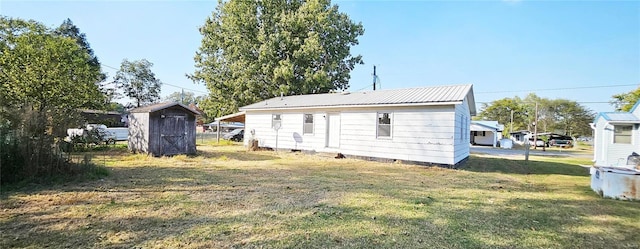 back of property featuring a storage unit, a yard, an outbuilding, and metal roof