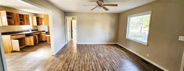 unfurnished dining area featuring ceiling fan, wood finished floors, and baseboards
