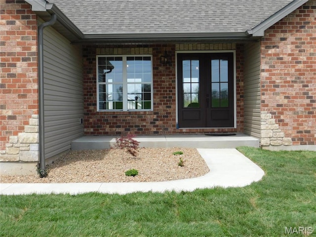 property entrance featuring roof with shingles, french doors, and brick siding