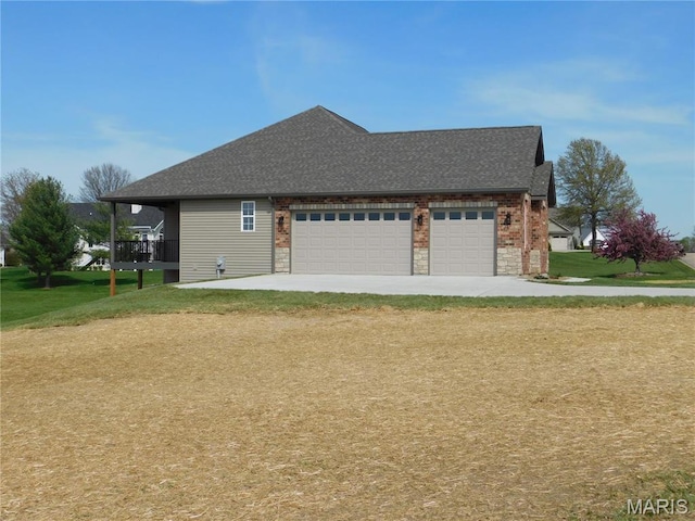 view of side of property with an attached garage, a yard, roof with shingles, and driveway