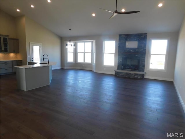 unfurnished living room with baseboards, plenty of natural light, a fireplace, recessed lighting, and high vaulted ceiling